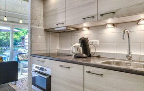 A modern kitchen with stainless steel appliances, a built-in oven, and a large window overlooking a deck area. - Amazing home in Bruinisse with kitchen (Bruinisse)