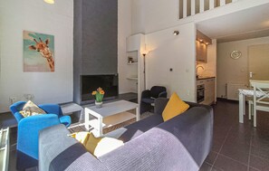 A modern living room with a sofa, chairs, a coffee table, a fireplace, and a kitchen area. - Amazing home in Bruinisse with kitchen (Bruinisse)