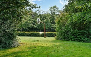 A well-maintained garden with a metal lamp post and a sign, surrounded by dense greenery and a grassy lawn. - Amazing home in Bruinisse with kitchen (Bruinisse)