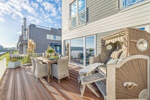 Una terraza con mobiliario de mimbre, comedor y vista de la ciudad.