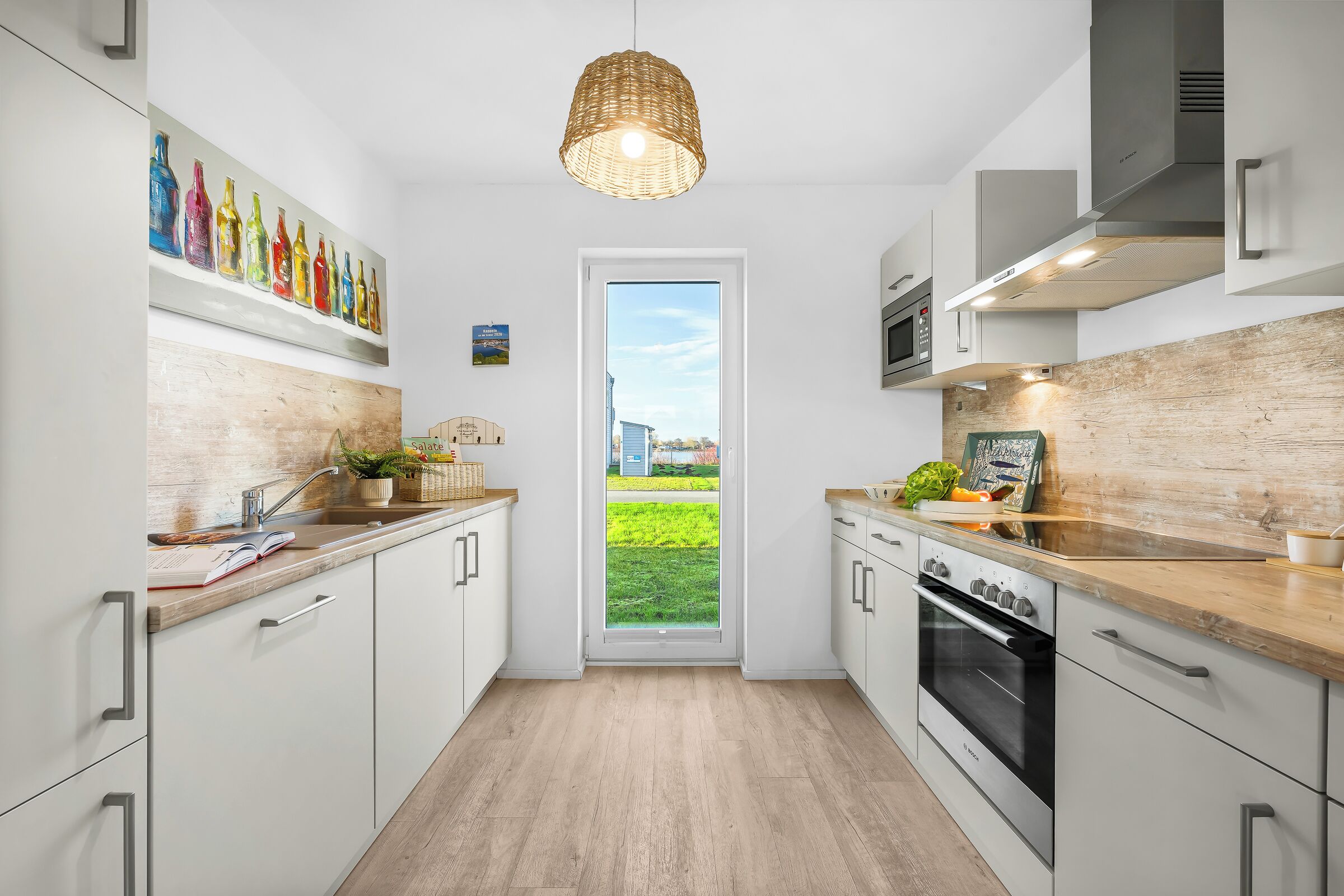 Une cuisine moderne avec des armoires blanches, un plan de travail en bois, un four en acier inoxydable et une grande fenêtre.