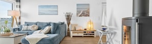 A modern living room with a sofa, a side table with a lamp, a bookshelf, and a fireplace. - Light-flooded villa with large terrace, direct waterfront, wellness area (Kappeln)