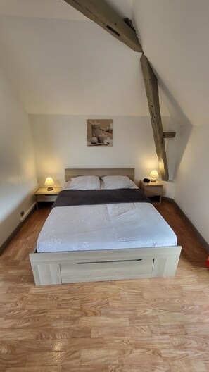 A bedroom with a wooden bed, two bedside tables with lamps, a wooden headboard, and a small picture on the wall. - Studio 7 - 3 min from Futuroscope - 1 to 4 persons (Chasseneuil-du-Poitou)