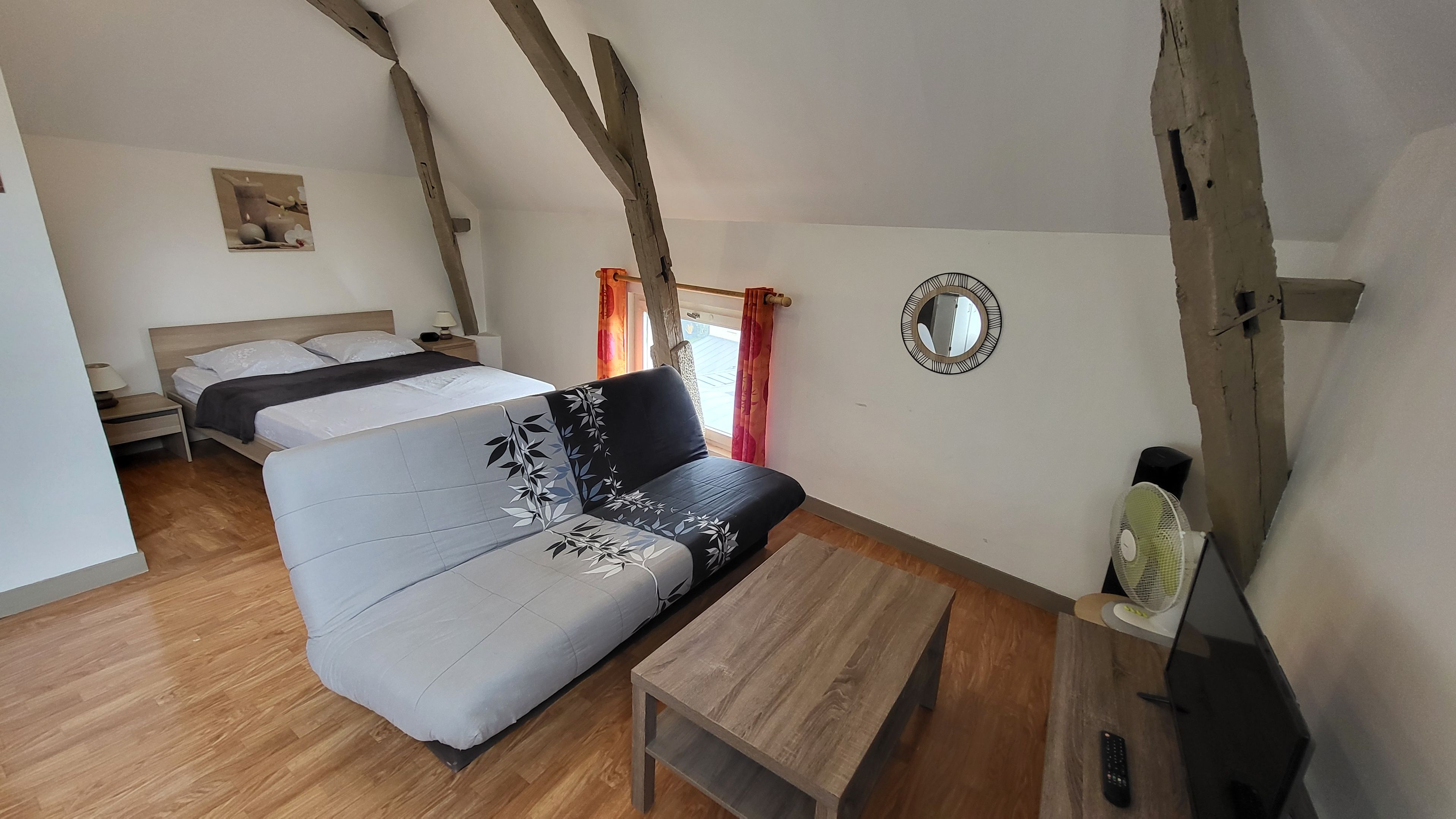 Une pièce comprenant un lit, un canapé, une table et un miroir.