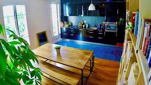 A modern kitchen with dark cabinets, a wooden dining table, and a bookshelf.