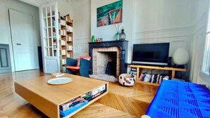 A living room with a fireplace, a TV, a bookshelf, and a coffee table.