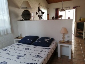 Cozy bedroom with a nautical-themed bed, nightstand, and table lamps, and decorative items on display.