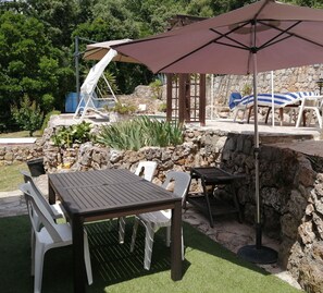 Relax in a serene outdoor space with a pool, lounge chairs, and a shaded area.