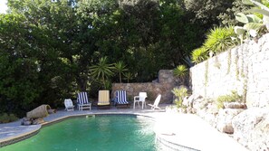 Relax by the serene pool surrounded by lush greenery and comfortable seating.