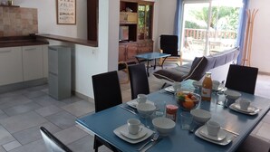A dining area with a table set for four, chairs, a blue tablecloth, and a view of the outdoors. - Apartment in detached house, quiet residential area "L'Orée du lac" (Biarritz)
