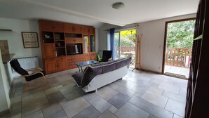 A spacious living area with a sofa, a dining table, and a kitchen area with wooden cabinets. - Apartment in detached house, quiet residential area "L'Orée du lac" (Biarritz)