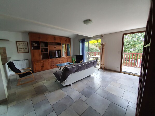 A spacious living area with a sofa, a dining table, and a kitchen area with wooden cabinets.