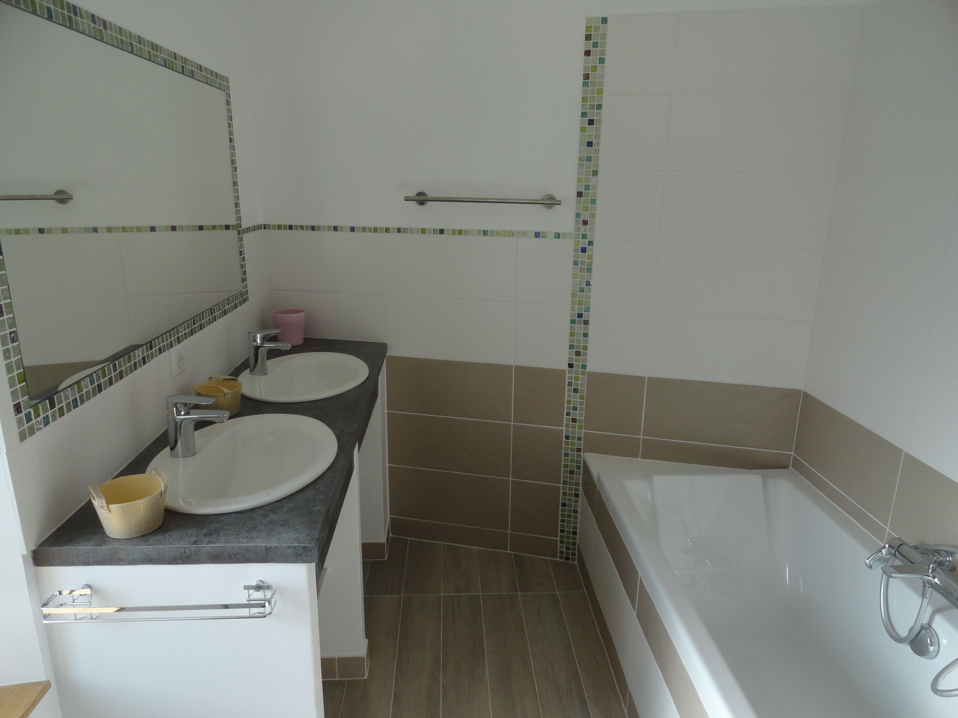 Un baño con dos lavamanos, un espejo, una bañera y un perchero para toallas.