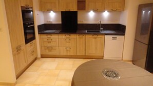 Cocina compacta con armarios de madera, horno empotrado, lavavajillas y refrigerador.