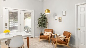 A room with a white dining table, two brown leather chairs, a small side table, a potted plant, and a gold pendant light. - Midtown Guest House - private entrance (Atlanta)