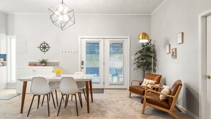 A dining area with a white table, four chairs, a hanging light fixture, and a door with a view to the outside. - Midtown Guest House - private entrance (Atlanta)