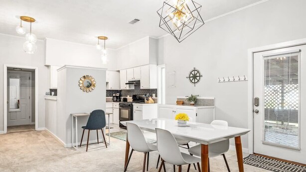 A modern kitchen with white cabinets, a dining area with a white table and chairs, and a decorative wall clock. - Midtown Guest House - private entrance (Atlanta)