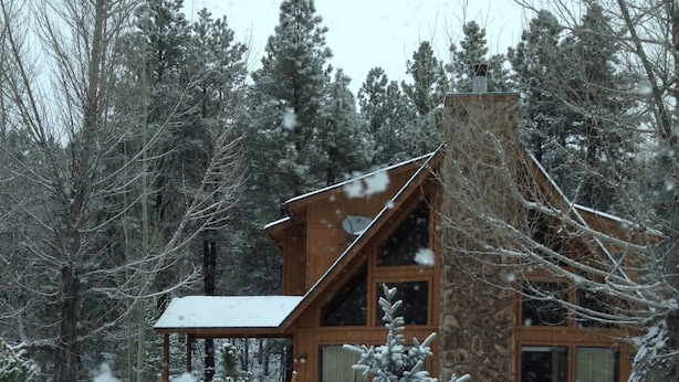A wooden cabin with a snow-covered roof, surrounded by snow-laden trees. - Cabin in the pines (Munds Park)