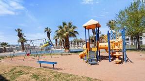 Un parque infantil con columpios, toboganes y una estructura para escalar.