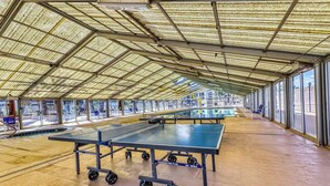 Zona de tenis de mesa techada en interior, con techo alto y ventanas amplias.