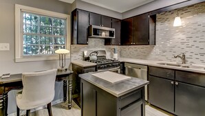 Une cuisine moderne avec des meubles de couleur sombre, une cuisinière à gaz et une grande fenêtre.