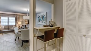 Un salon moderne avec un canapé, une table à manger et des chaises. Un tableau est accroché au mur, et il y a une armoire blanche avec une porte.
