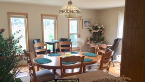 Un coin repas avec une table ronde, des chaises, un ventilateur et un lustre.