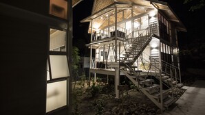 Eine mehrstöckige Holzkonstruktion mit Treppe, erleuchteten Fenstern und Blick auf die Umgebung.