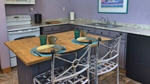 Una cocina compacta con una isla central, un microondas, una estufa y un lavamanos.