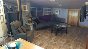 Una sala de estar con sofá, sillón, mesa de centro y televisor.