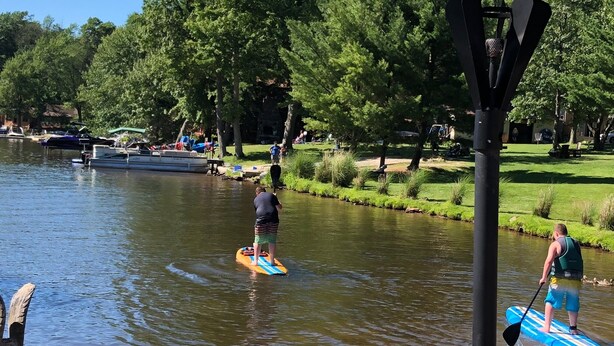 Une rivière paisible où l’on peut faire du paddle, du bateau, et un parc avec des arbres et des bancs.