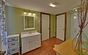Une salle de bain avec un meuble-lavabo blanc, un miroir, un évier et un espace douche.
