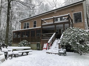 A wooden cabin with a covered porch, a staircase, and a picnic table set up outside. - 1,000 Ft Creekfront | Hot Tub, Fire Pit, Games, Direct Trail Access & Dogs OK (Cherry Log)
