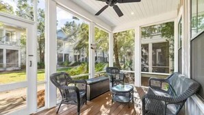 Eine überdachte Terrasse mit Korbmöbeln und einem Deckenventilator.