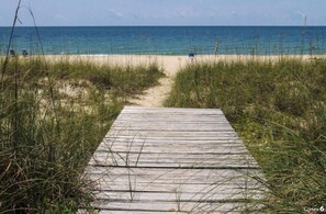 Un muelle de madera que conduce a una playa con aguas azules y cristalinas.
