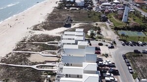 Zona costanera amb accés a la platja, un aparcament i diversos edificis d'estil arquitectònic uniforme.