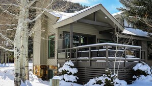 Ett modernt hus i två våningar med en inglasad veranda och ett snötäckt landskap.