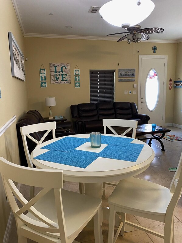 A dining area with a round table, white chairs, and a ceiling fan.