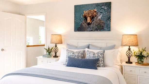 Um quarto com uma cama, duas mesas de cabeceira com luminárias, um espelho e um quadro na parede.