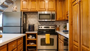 A kitchen with wooden cabinets, stainless steel appliances, and a patterned backsplash.
