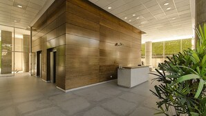 Un vestíbulo moderno con una pared de madera, una recepción y una planta grande.