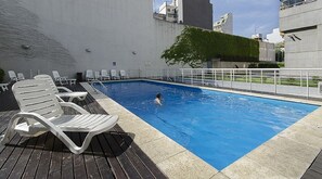 Une piscine sur le toit, dotée de chaises longues et offrant une vue sur le panorama urbain.