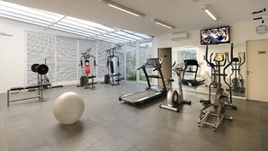 Un gimnasio con máquinas de cardio, equipo de levantamiento de pesas y una pelota grande para ejercicio.