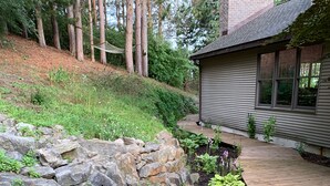 A wooden deck with a stone retaining wall and garden beds. - Spacious, minutes from Traverse City, Williamsburg a country setting. 2700 sq.  (Williamsburg)
