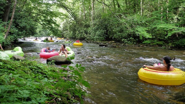 People floating on river rafts in a forested area.