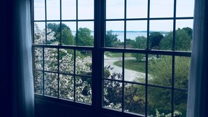 A view through a window with a grid pattern, overlooking a landscape with trees and a body of water. - Spacious, minutes from Traverse City, Williamsburg a country setting. 2700 sq.  (Williamsburg)