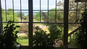 A view through a large window with multiple panes, overlooking a well-maintained garden and a body of water. - Spacious, minutes from Traverse City, Williamsburg a country setting. 2700 sq.  (Williamsburg)