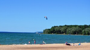 A beach with people sunbathing and a kite flying in the sky. - Spacious, minutes from Traverse City, Williamsburg a country setting. 2700 sq.  (Williamsburg)