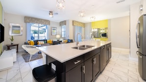 A modern kitchen with a large island, stainless steel appliances, and a dining area with a sofa and chairs. - (NF4909) Home 4/3 Private Pool & Free Waterpark (Kissimmee)
