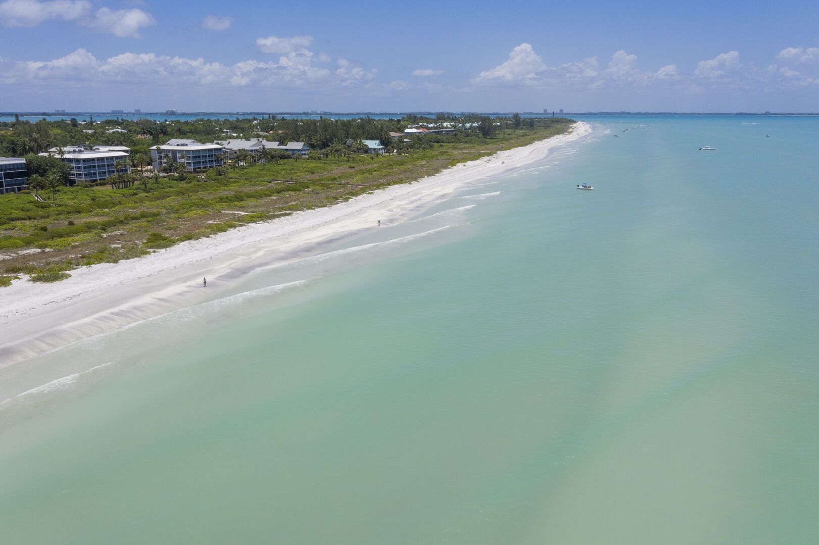 A coastal area with a beach, buildings, and clear water.